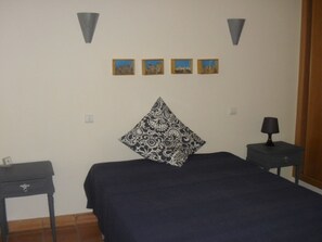 Ein Schlafzimmer mit einem Bett, einem Nachttisch, einer Lampe und drei gerahmten Bildern an der Wand.