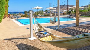 Un espace aménagé au bord de la piscine, avec un hamac, des chaises longues et des parasols.