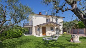 A two-story house with a stone facade, a balcony, and a well-maintained lawn with two sun loungers. - Villa Lisi With Pool (Bardolino)