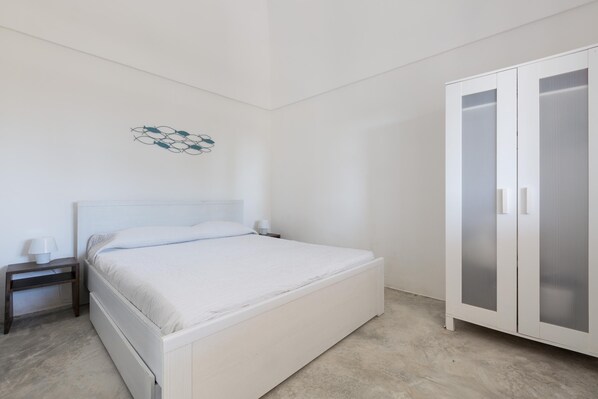 Un dormitorio con cama, mesita de noche, lámpara de pared y armario.
