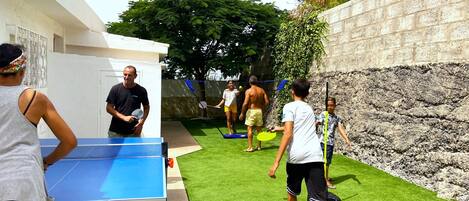 A group of people playing table tennis outdoors.