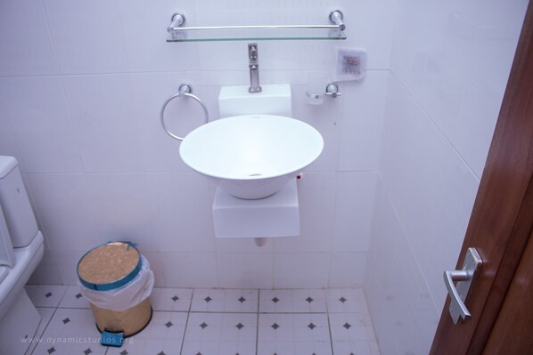 A small bathroom with a white toilet, a white sink, and a trash can.