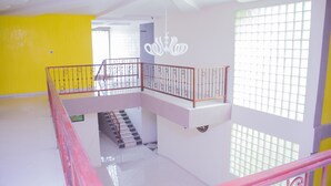 Un interior de varios niveles con una escalera, una araña y un ventanal de diseño calado.