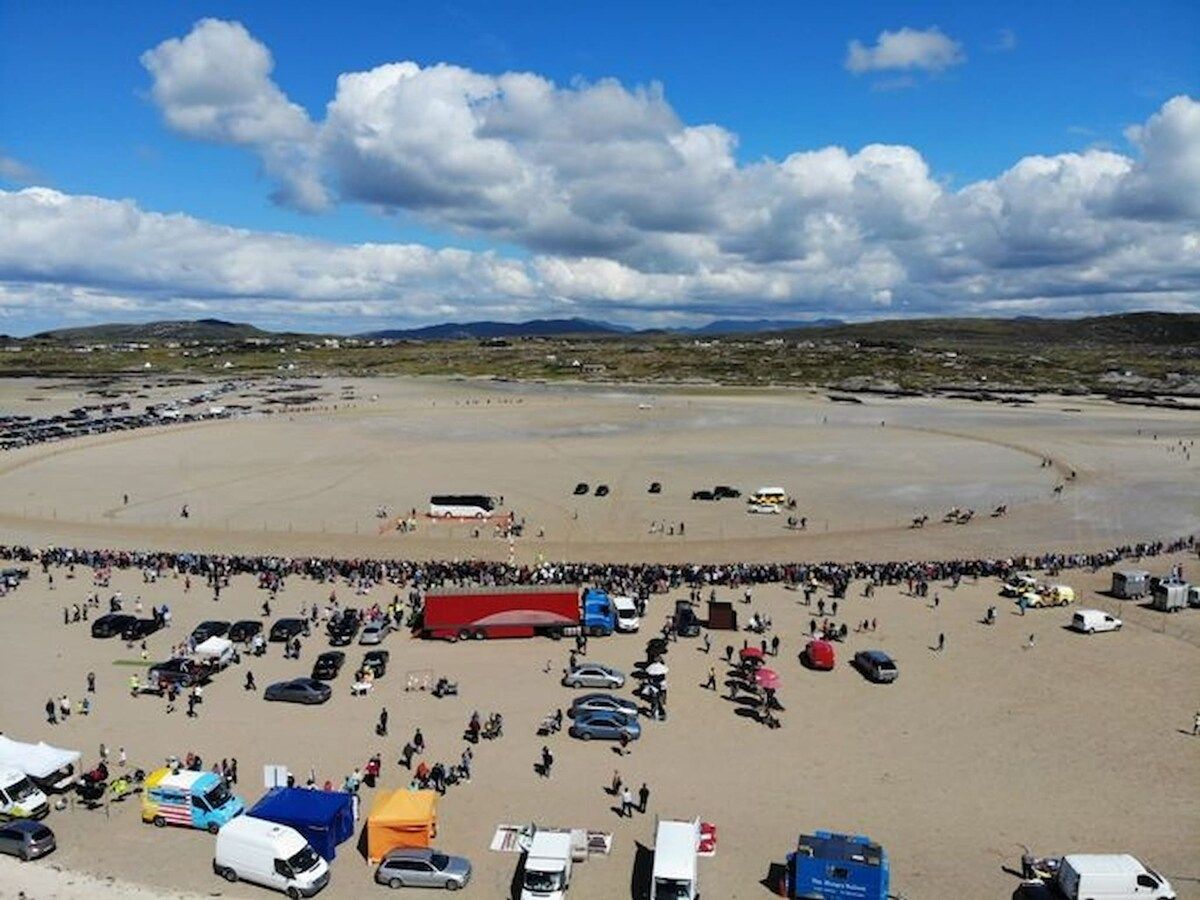 A large open area with a crowd, vehicles, and tents.