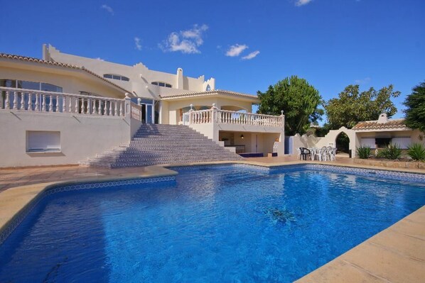 A swimming pool with a staircase leading to a building, surrounded by a clear blue sky. - Villa Cora - Javea, Costa Blanca (Javea)