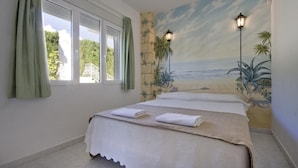 A bedroom with a bed, a mural of a beach scene, and two wall-mounted lamps. - Villa Cora - Javea, Costa Blanca (Javea)