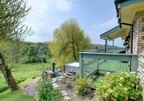 Relax in a serene garden setting with a hot tub and shaded deck.