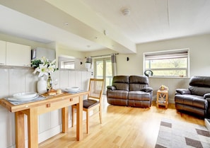 Relax in this inviting space with a dining table for two, a sofa, and armchairs.