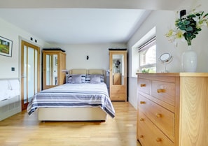 Relax in this serene bedroom with a large bed, two bedside tables, and a dresser.