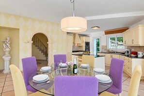 A dining area with a glass table, purple chairs, and a chandelier. - Villa Jarmila - Javea, Costa Blanca (Javea)