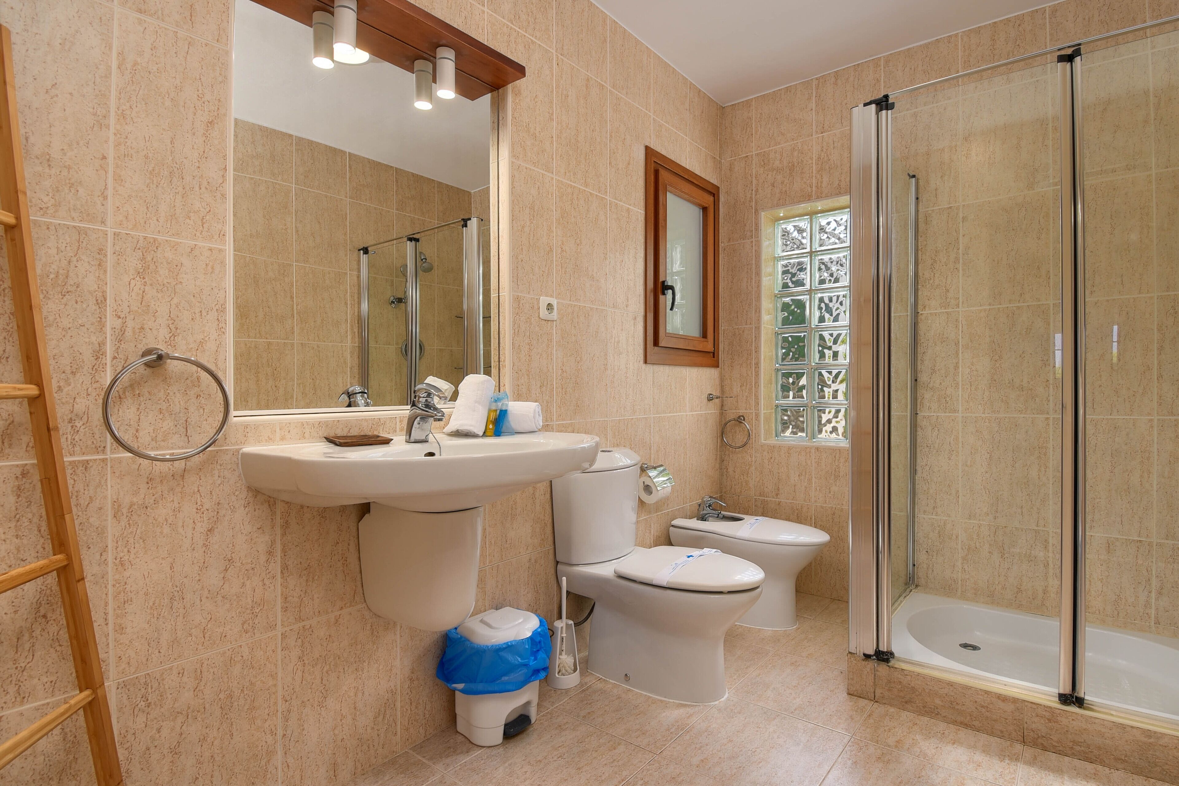 A modern bathroom with a sink, toilet, bidet, and glass-enclosed shower.