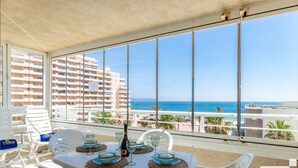 Un balcó amb taula per a dues persones, amb vista a una platja i un edifici alt.