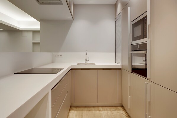 A compact kitchen with a sink, a microwave, and a built-in oven.