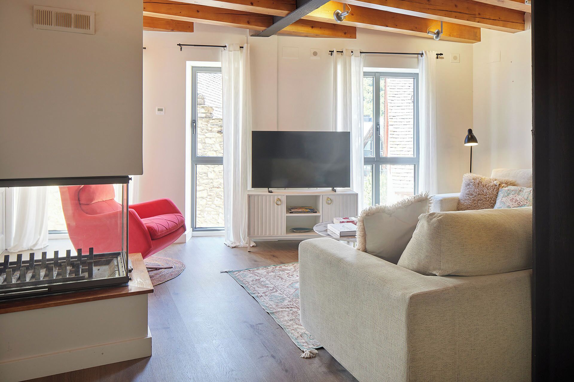 Ein Wohnzimmer mit Fernseher, rotem Sessel und weißem Sofa.