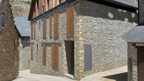 A stone building with wooden slats and a sloped roof, surrounded by similar structures in a rural setting. - Val Arties 3 by FeelFree Rentals (Arties)
