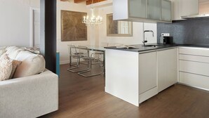 A modern kitchen with a central island, a dining area with a chandelier, and a cozy seating area with a patterned sofa. - Val Arties 3 by FeelFree Rentals (Arties)