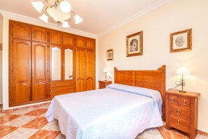 Une chambre à coucher avec un grand lit, une armoire en bois et deux tables de chevet avec des lampes.