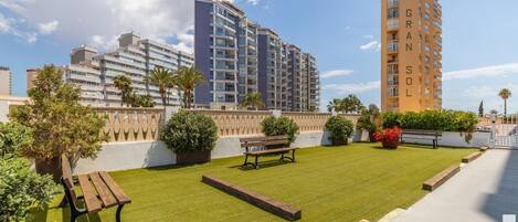 A well-maintained outdoor area with a grassy lawn, benches, and potted plants.