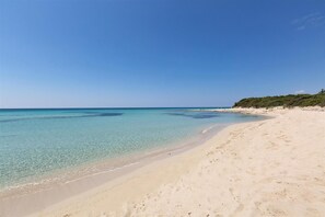 A sandy beach with clear turquoise water and a distant shoreline. - Riva del Conte by BarbarHouse (Riva degli Angeli)