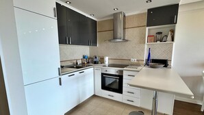 Een moderne keuken met witte kasten, een roestvrijstalen afzuigkap, een inbouwoven en een spoelbak.
