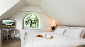 A bedroom with a bed, a desk, a TV, and a window with a view of the sea. - A recently converted Kent ragstone coach house near Sevenoaks. (nr Sevenoaks)
