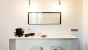 A clean, modern bar area with a coffee machine, a Nespresso machine, and a framed artwork above the counter. - Chueca Urban (Madrid)