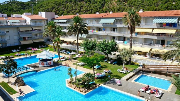Un hôtel doté de plusieurs piscines, de palmiers et surplombant un paysage montagneux.