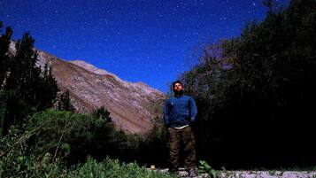 Une personne se tient à l’extérieur, la nuit, sous un ciel étoilé.