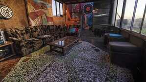 Una habitación rústica con suelo de mosaico, un sofá, una mesita de centro y un mural en la pared.