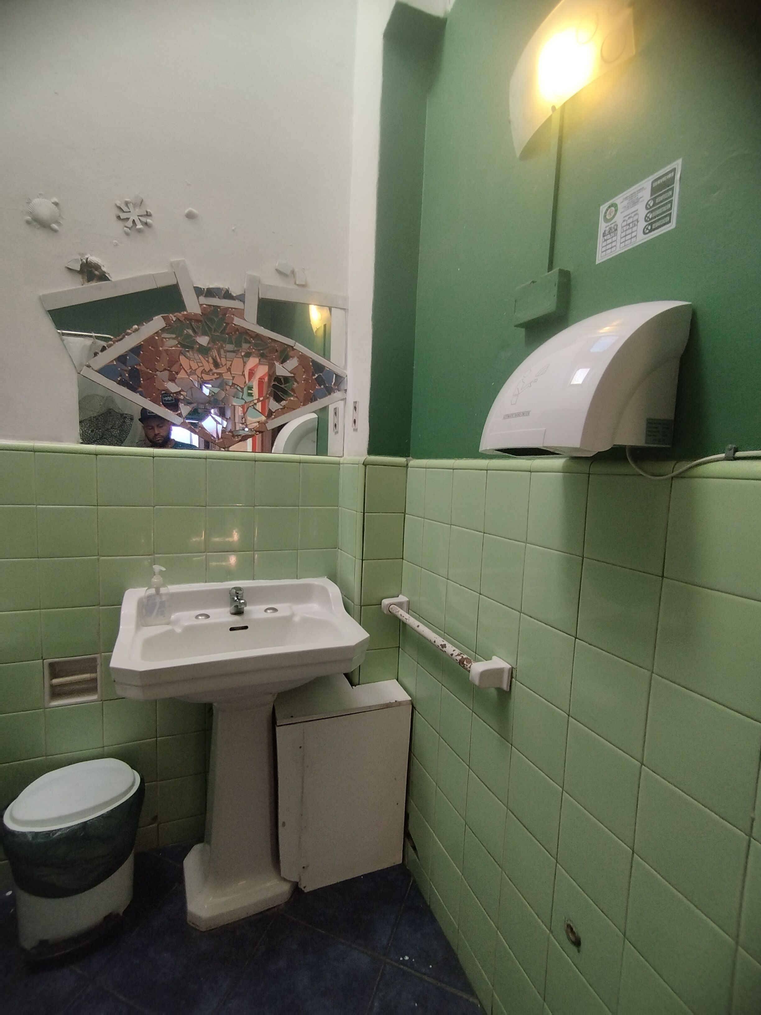 Un baño con lavamanos, inodoro y secador de manos.