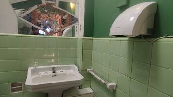 Un baño con lavamanos, inodoro y secador de manos.