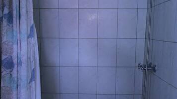 A small bathroom with a shower, toilet, and a patterned floor.