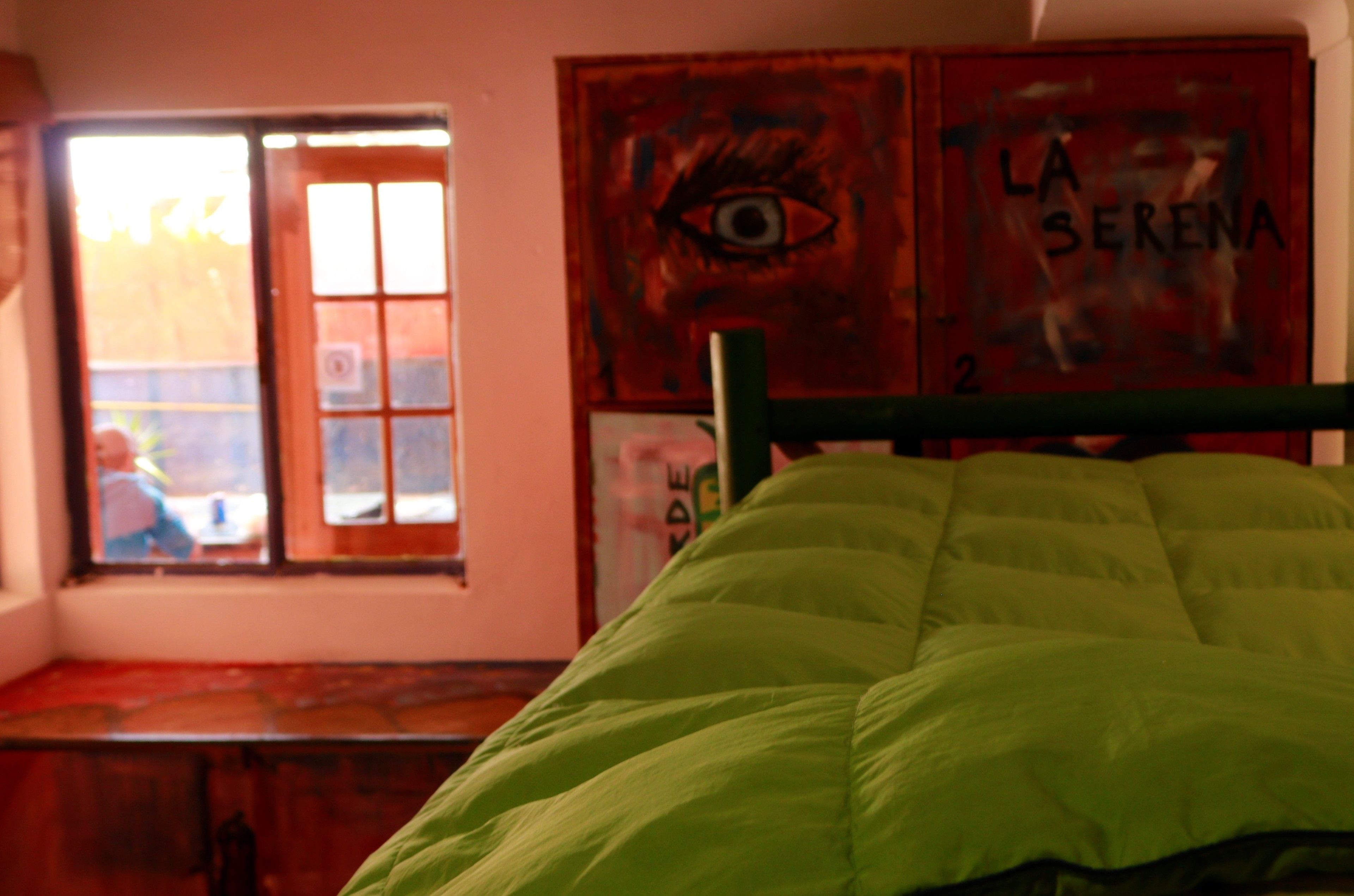 Een kamer met een bed, een raam en een muur met een schilderij.
