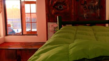 Een kamer met een bed, een raam en een muur met een schilderij.