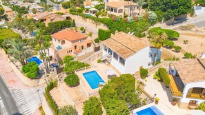 An aerial view of a residential area with multiple houses, a swimming pool, and lush greenery. - Villa Quimera - PlusHolidays (Benissa)