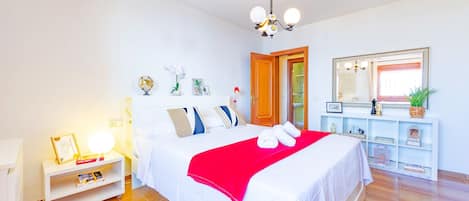 A neatly arranged bedroom with a bed, bedside table, and a mirror.