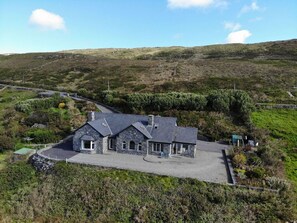 A stone house with a paved driveway and a fenced garden. - Once Upon a Tide (Clifden)