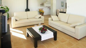 A living room with two white sofas, a dark coffee table with a white cloth, and a black fireplace.