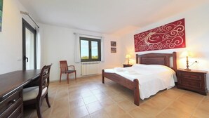 A bedroom with a bed, bedside tables, a chair, a desk, and a window.