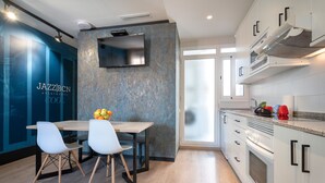 A modern kitchen with a wooden dining table, white chairs, and a blue accent wall. - Cool Jazz 81 - Habitat Apartments (Barcelona)