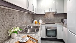 A modern kitchen with granite countertops, stainless steel appliances, and white cabinetry.