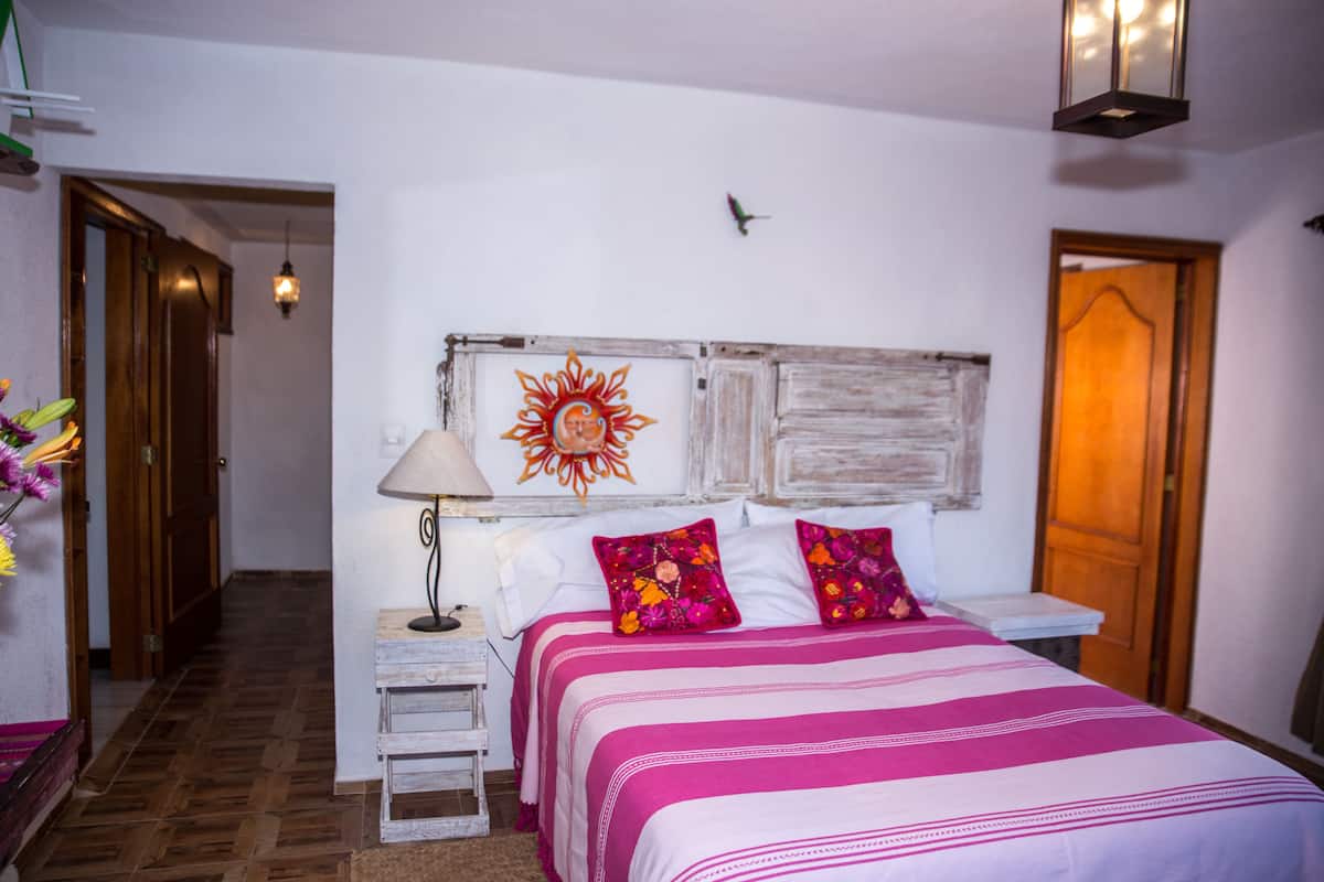 Une chambre à coucher avec un lit, une table de chevet, une lampe et un élément décoratif mural.