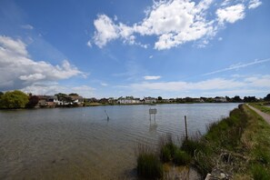 A calm lake with a clear sky, surrounded by houses and a grassy path. - Dolphin House, Emsworth -  a flat that sleeps 2 guests  in 1 bedroom (Emsworth)