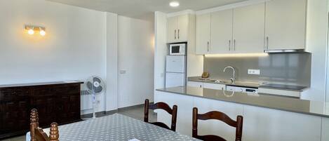 Una cocina moderna con armarios blancos, un microondas y una campana extractora de acero inoxidable.