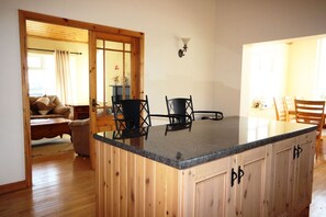 Een keuken met houten kastjes, een granieten aanrecht en een eethoek met stoelen.