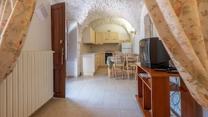 A compact kitchen with wooden cabinets, a dining table with chairs, a television, and a radiator. - Ancient farm among the olive trees with pool in the Itria Valley (Provincia di Taranto)