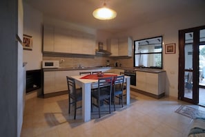 A modern kitchen with a dining table and chairs, a microwave, stove, and a large window.