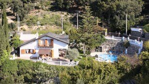 A house with a balcony, a swimming pool, and a garden.