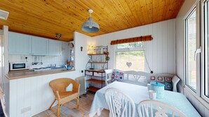 A cozy cabin interior with a kitchen, dining area, and a window with a view. - F67 Ischia, Riviere Towans (Hayle)
