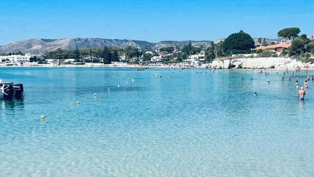 A clear coastal area with people swimming and sunbathing, a boat docked on the left, and buildings in the background. - Villa Sicily Pool & Beach,  private pool a few steps from the beach and the sea (Fontane Bianche)